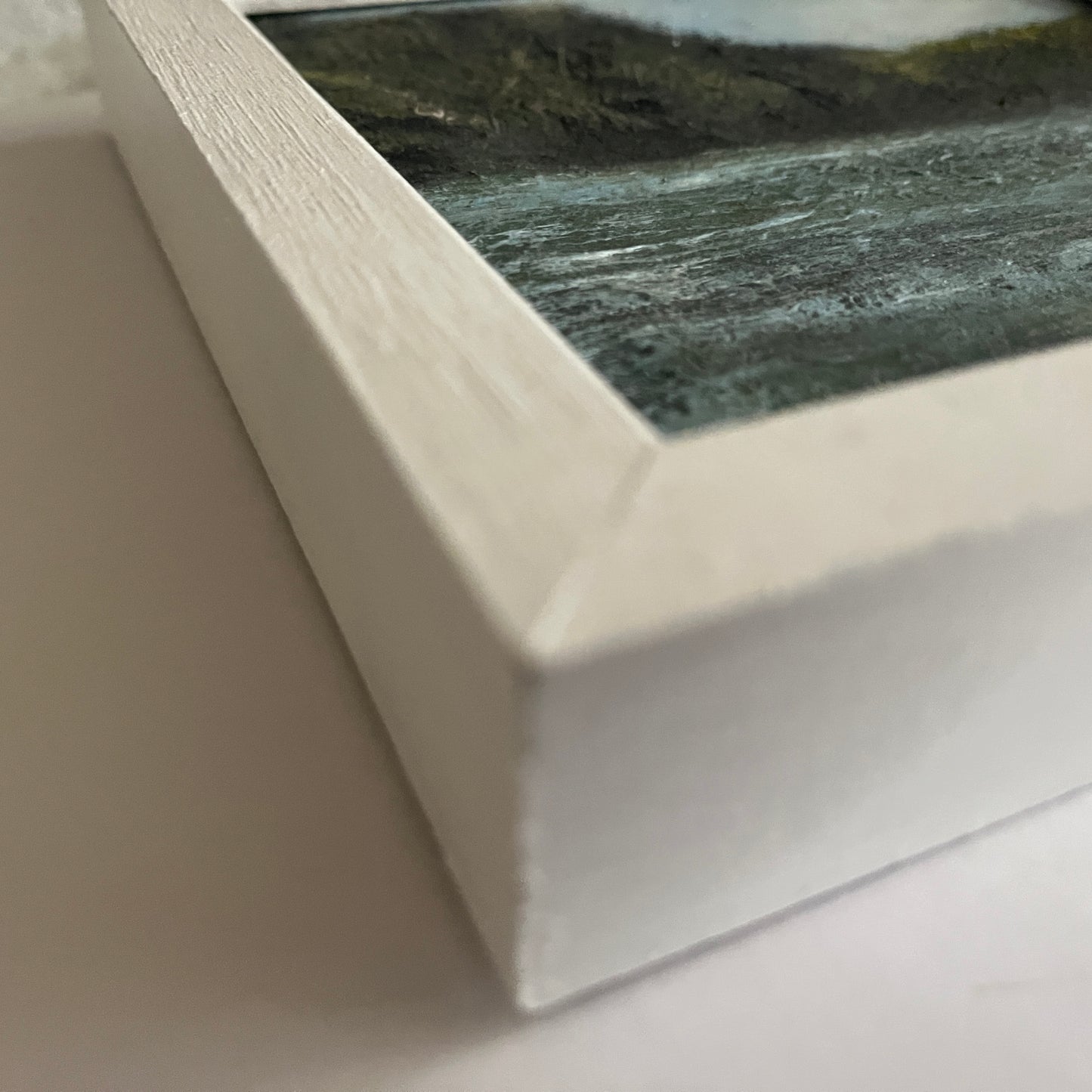 Framed artwork of a landscape with a river and mountains. framed oil painting of river and trees and birds in a white wooden frame