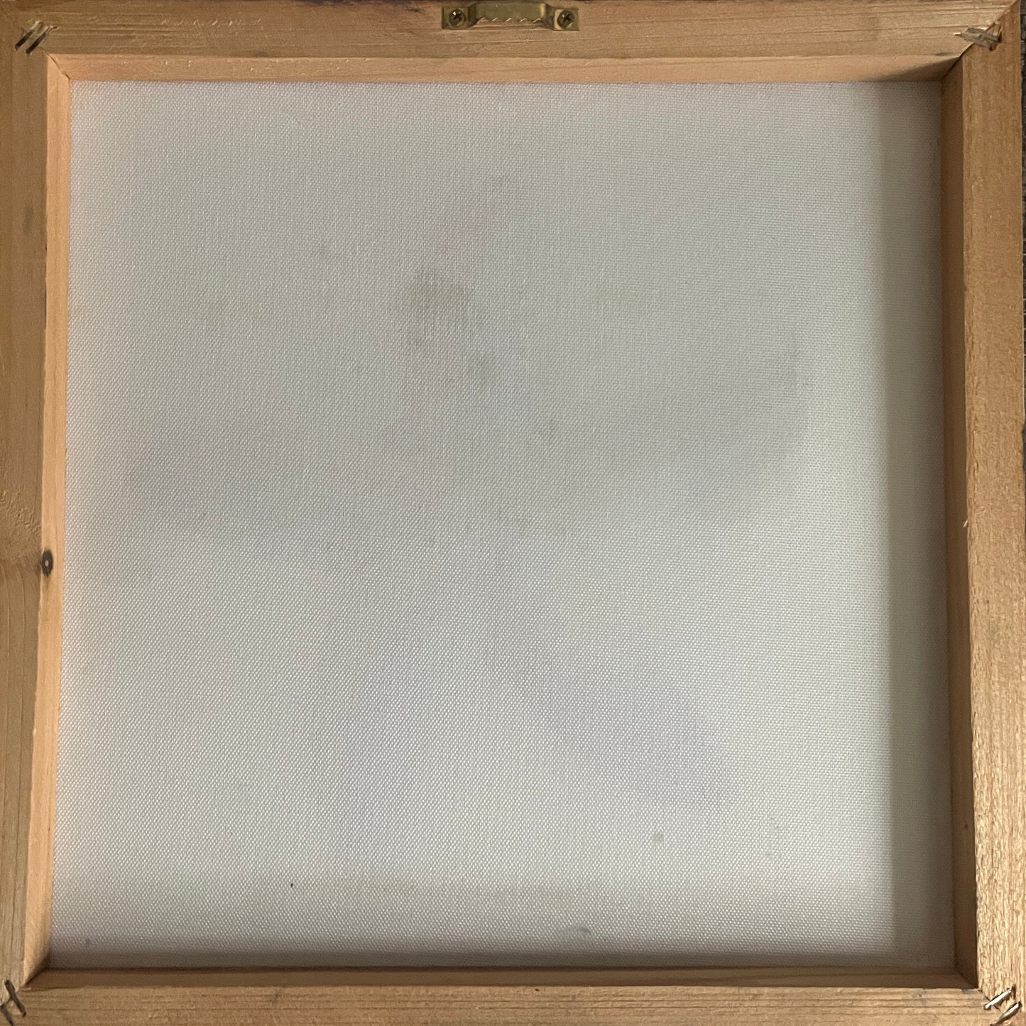 The back side of a square wooden-framed canvas or print, showing a light natural wood border, a white canvas surface, and a metal hanging bracket at the top.