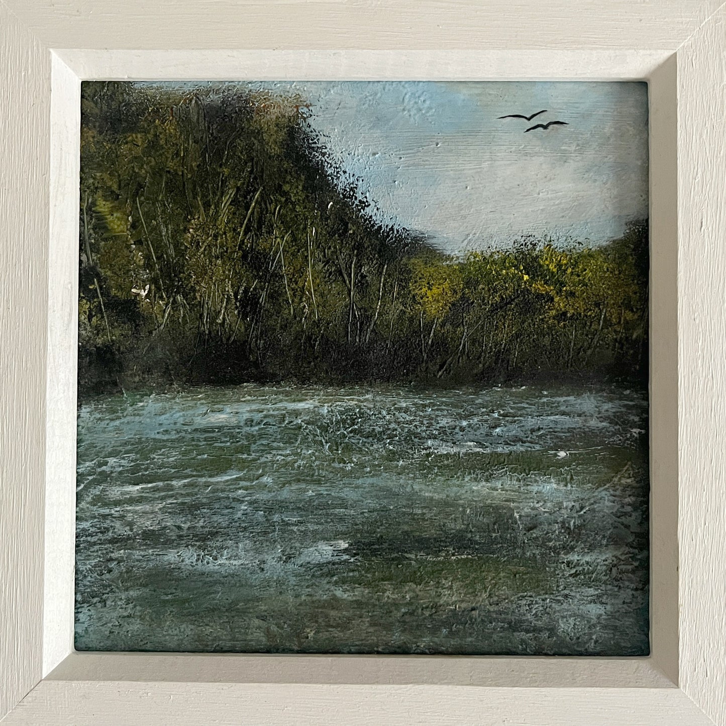 Framed painting of a natural landscape with water, trees, and birds.  framed oil painting of river and trees and birds in a white wooden frame