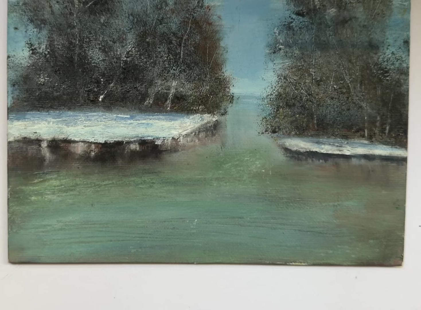 An impressionistic landscape painting of a calm river or inlet between two dark, snow-dusted tree islands under a blue sky, rendered with visible brush texture.